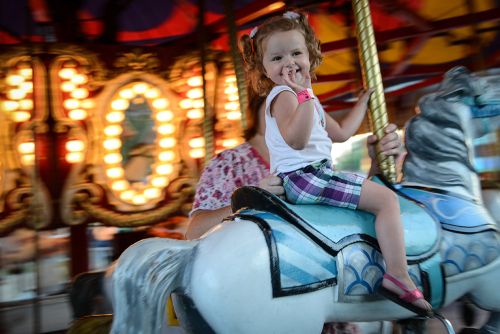 The image is of a little girl on a carousel at the Genesee county fair. 