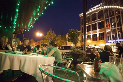 The image is of Blackstones restaurant at night with a group of people enjoying their dinner. The street is covered in lights.