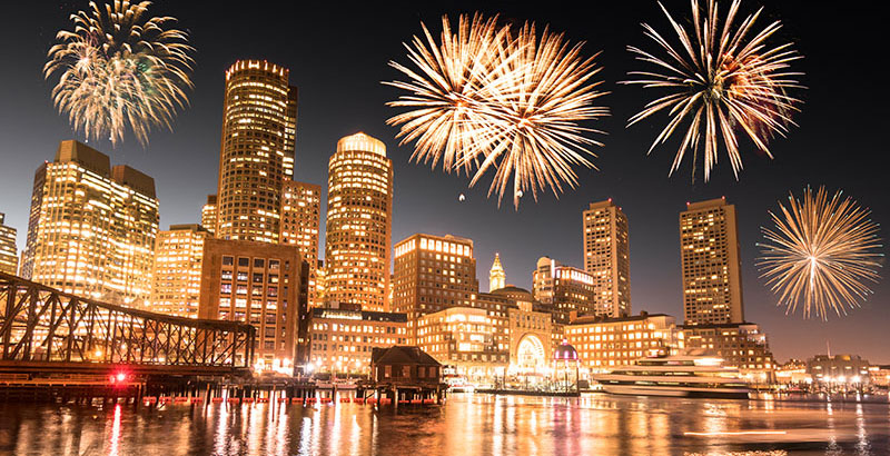 Boston skyline at night with fireworks over the buildings.